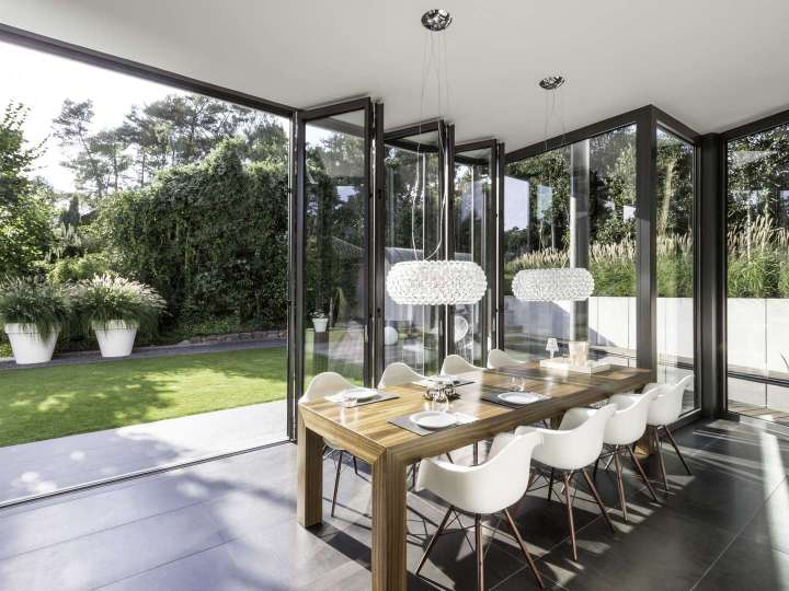 Wintergarten mit geöffneter Glas-Faltwand mit Blick ins Grüne