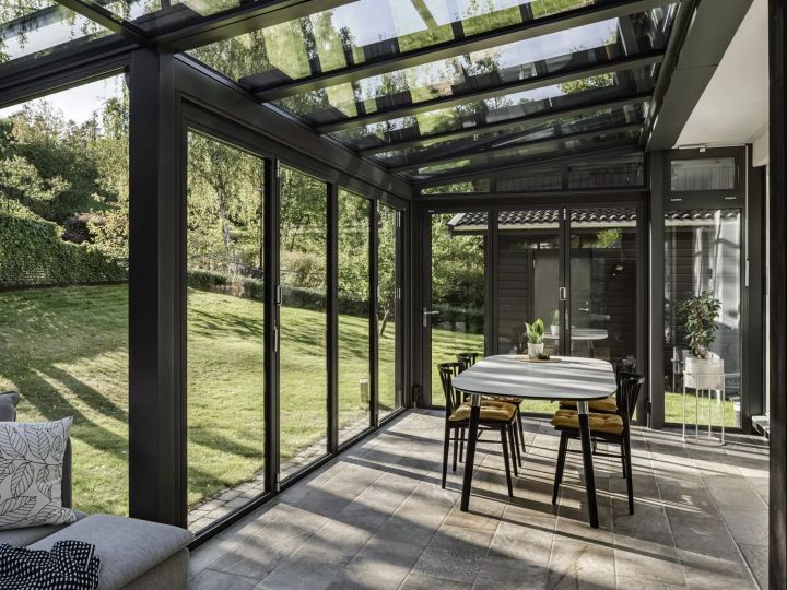 Wintergarten mit Blick in den Garten und Esstisch im Zentrum