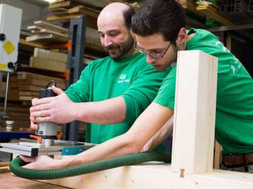zwei Männer bearbeiten ein Stück Holz